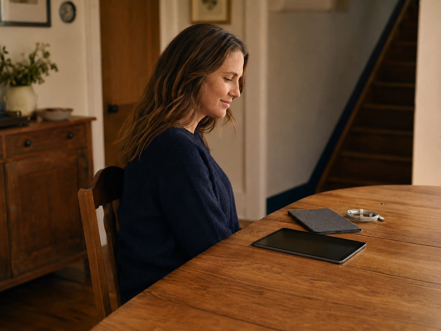 A customer looking at a tablet beside a folio and charging cable on a dining table
