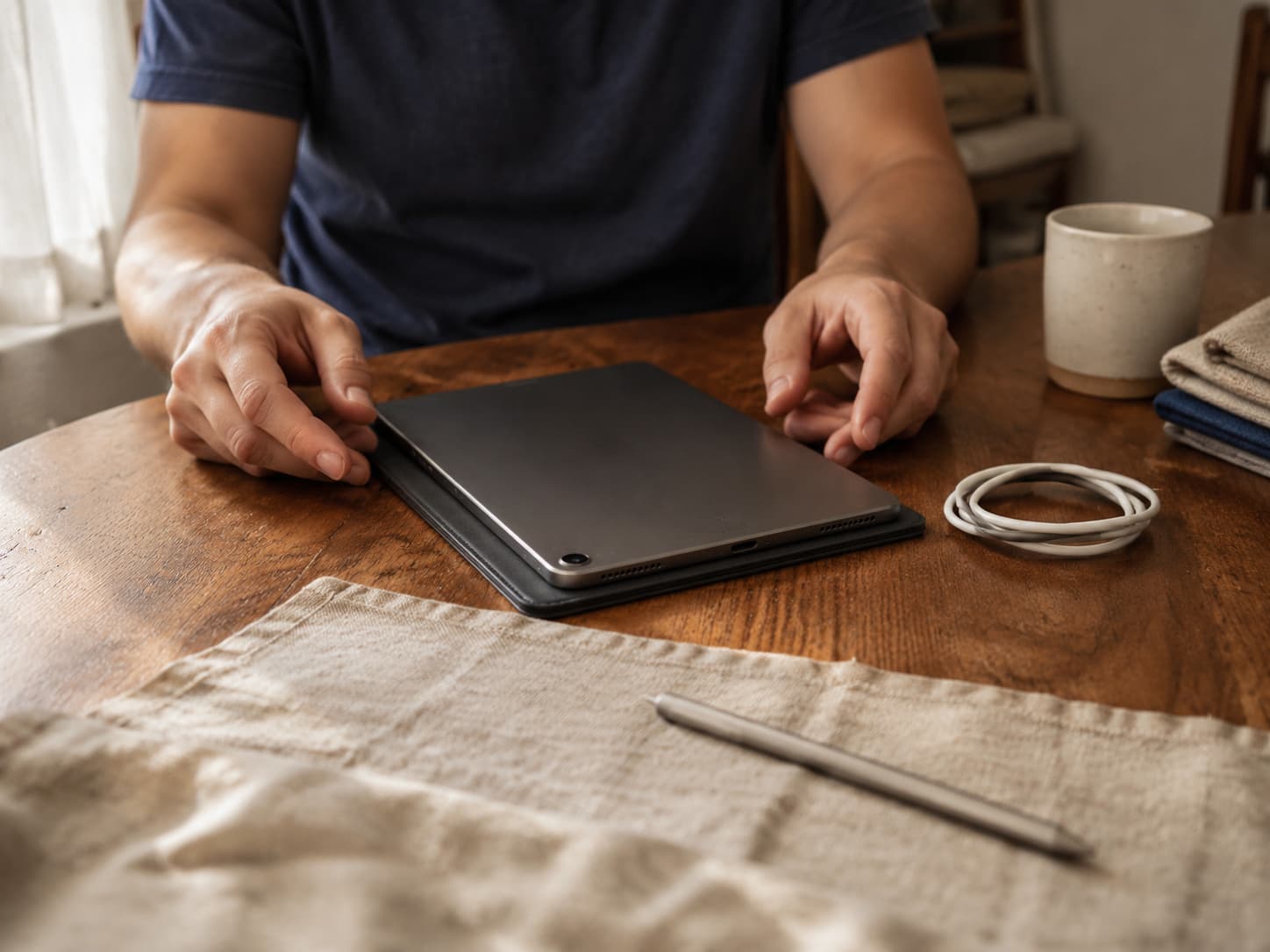 A tablet resting on its folio beside a stylus and cable while its condition is checked