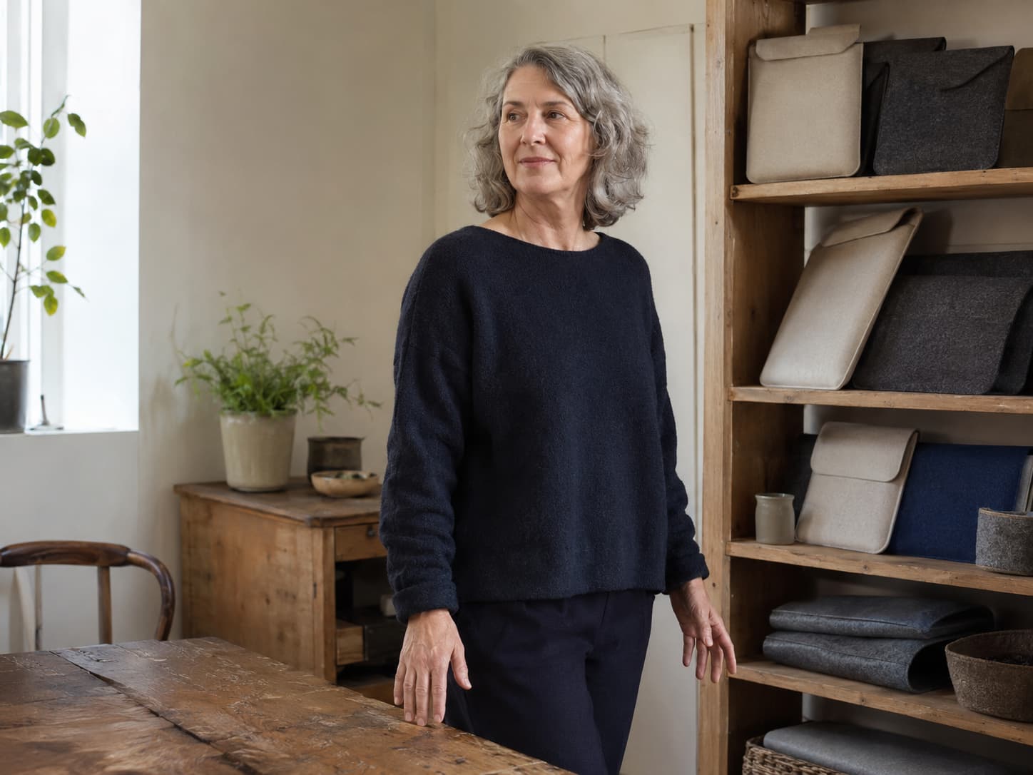 An older adult standing beside shelves of plain felt device sleeves in a modest operations office